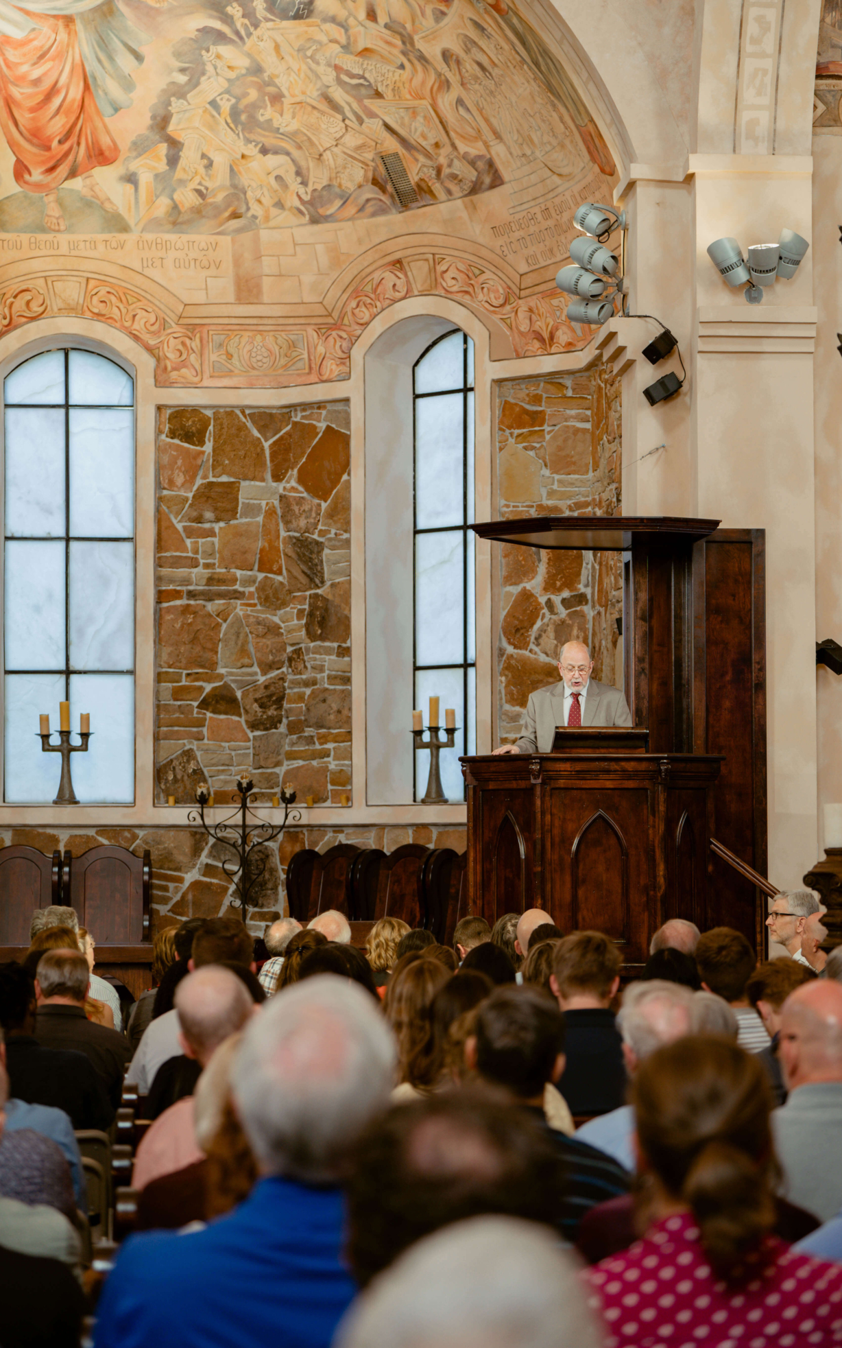 N.T. Wright speaking from inside a pulpit, which is attached to the building and raised up above the crowd.