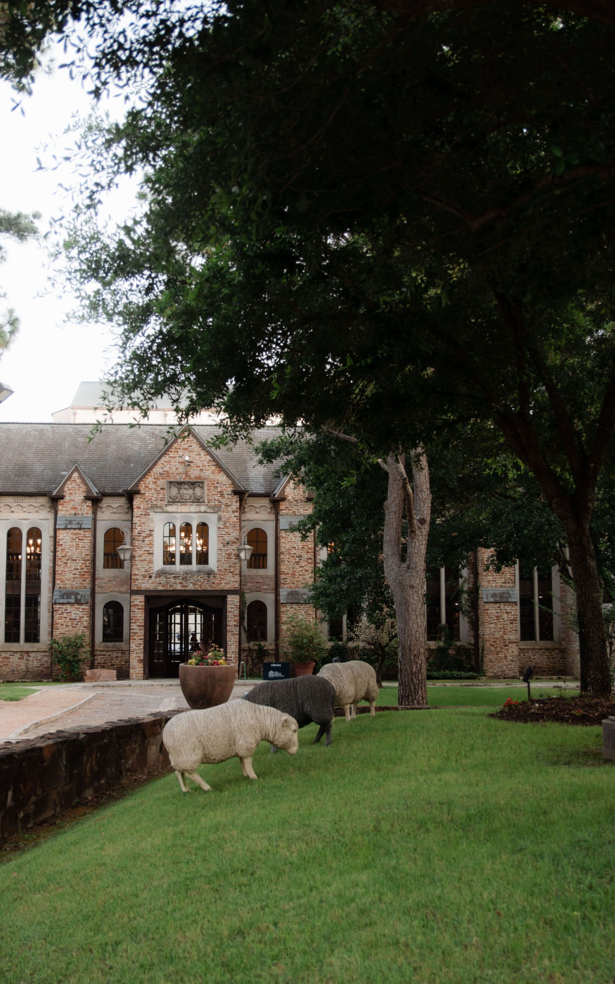 The library as seen from the village. In the foreground, artificial sheep appear to graze the hill of grass they are on.