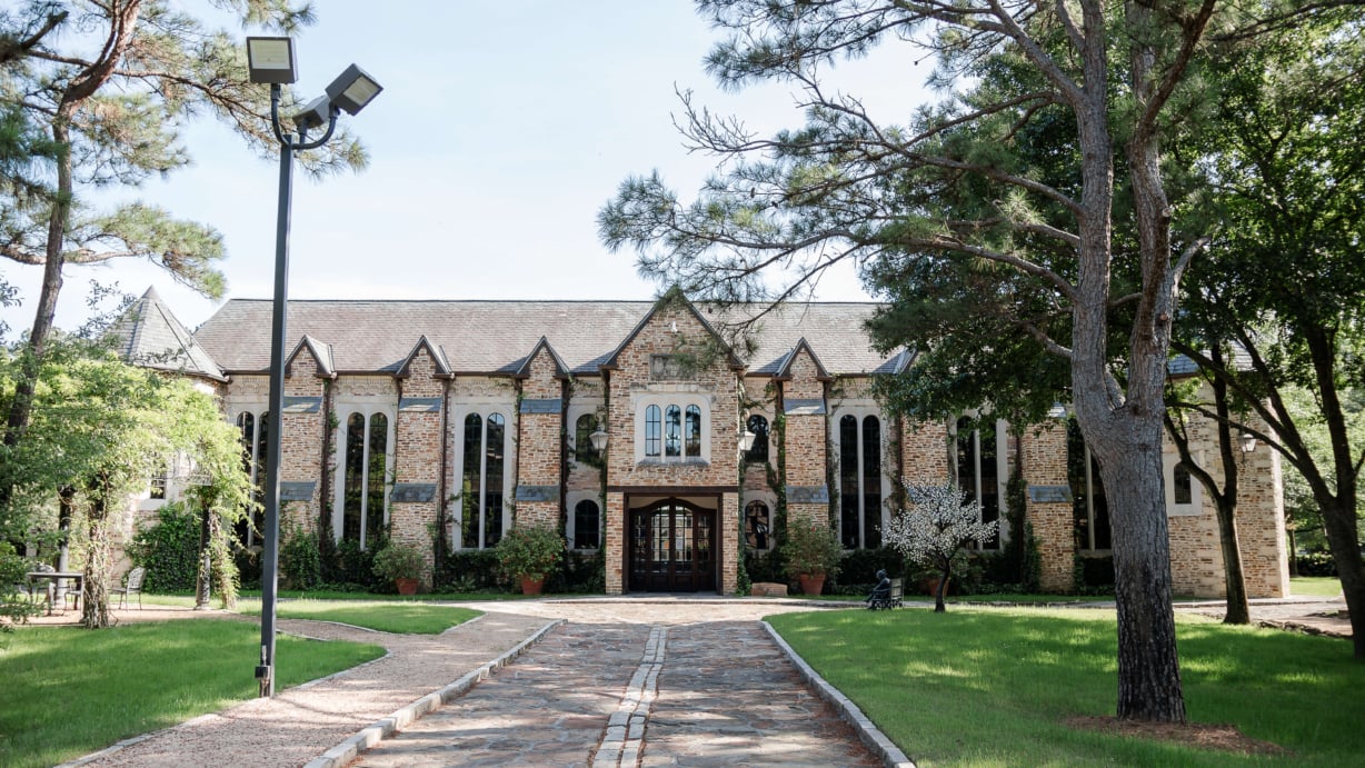 The front entrance of the library with trees on either side of a stone pathway