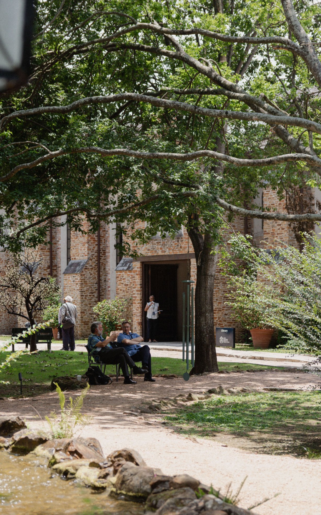 Two men converse on a bench outside the library